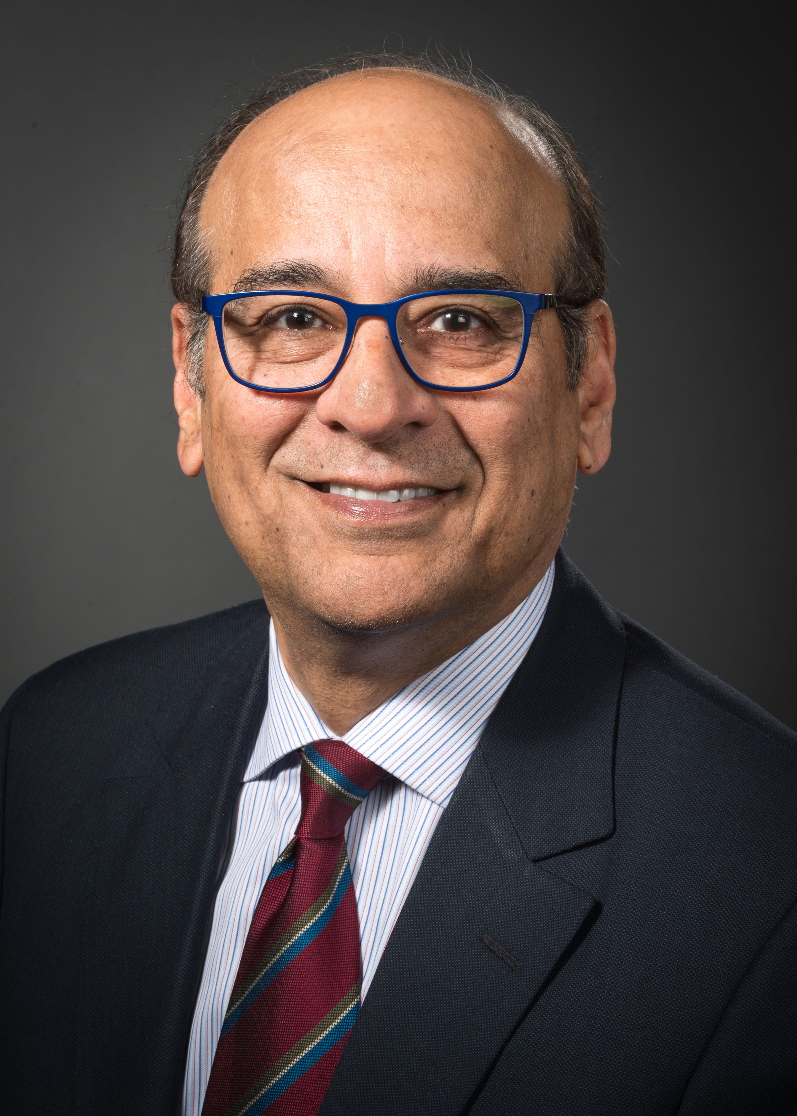 Raj Narayan, MD, head shot wearing a maroon tie with blue stripes and blue glasses